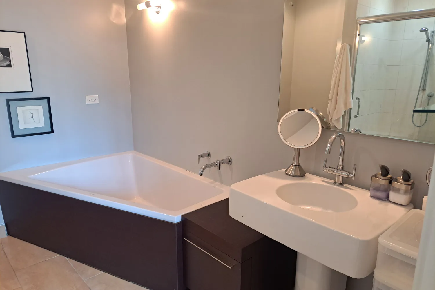 Clean modern bathroom with a corner soaking tub, wall-mounted faucet, and white sink
