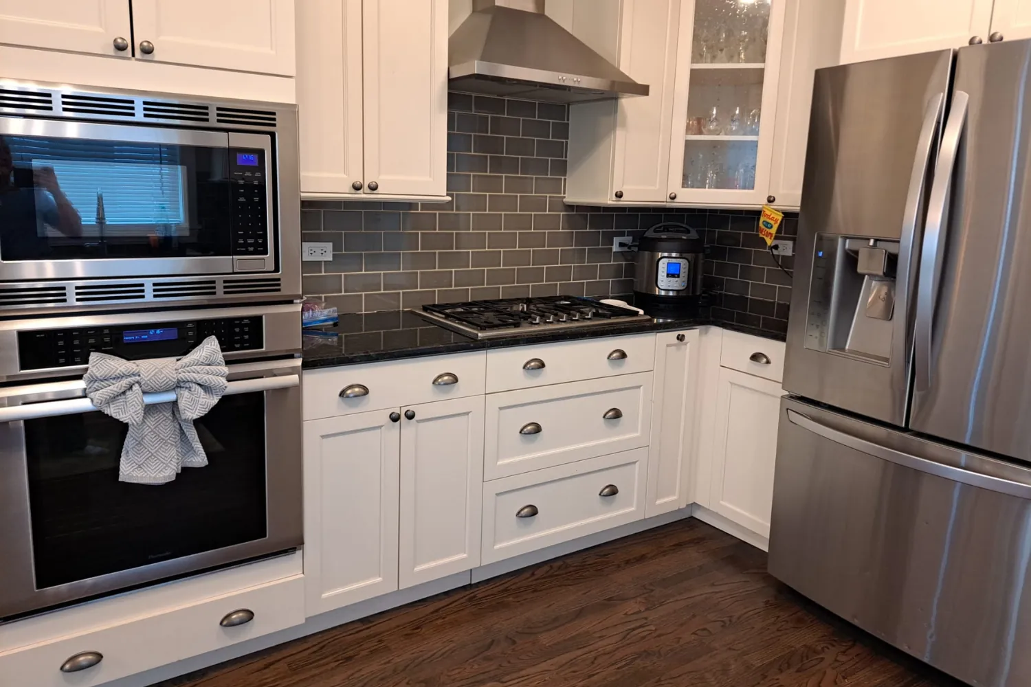 Clean white kitchen with a stainless wall oven, gas cooktop, and gray subway tile backsplash